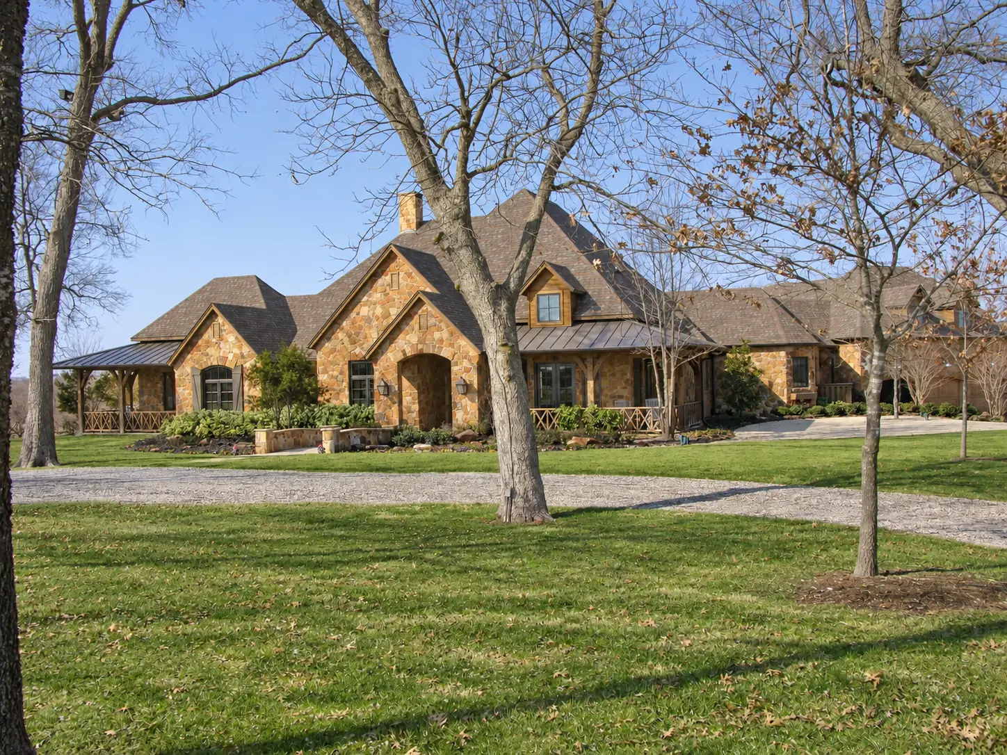 Stone country home with layered gables beneath mature trees